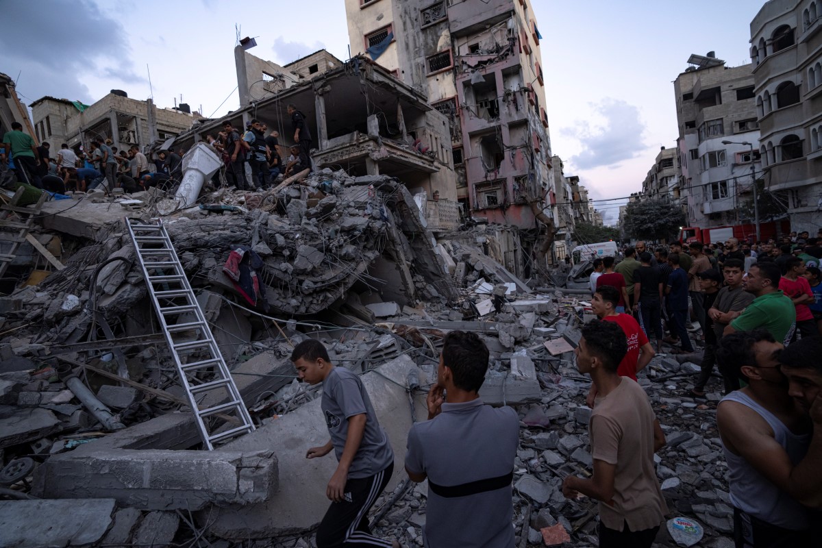 Palestinians look for injured in the rubble of a destroyed residential building following an Israeli airstrike, Tuesday, Oct. 10, 2023.